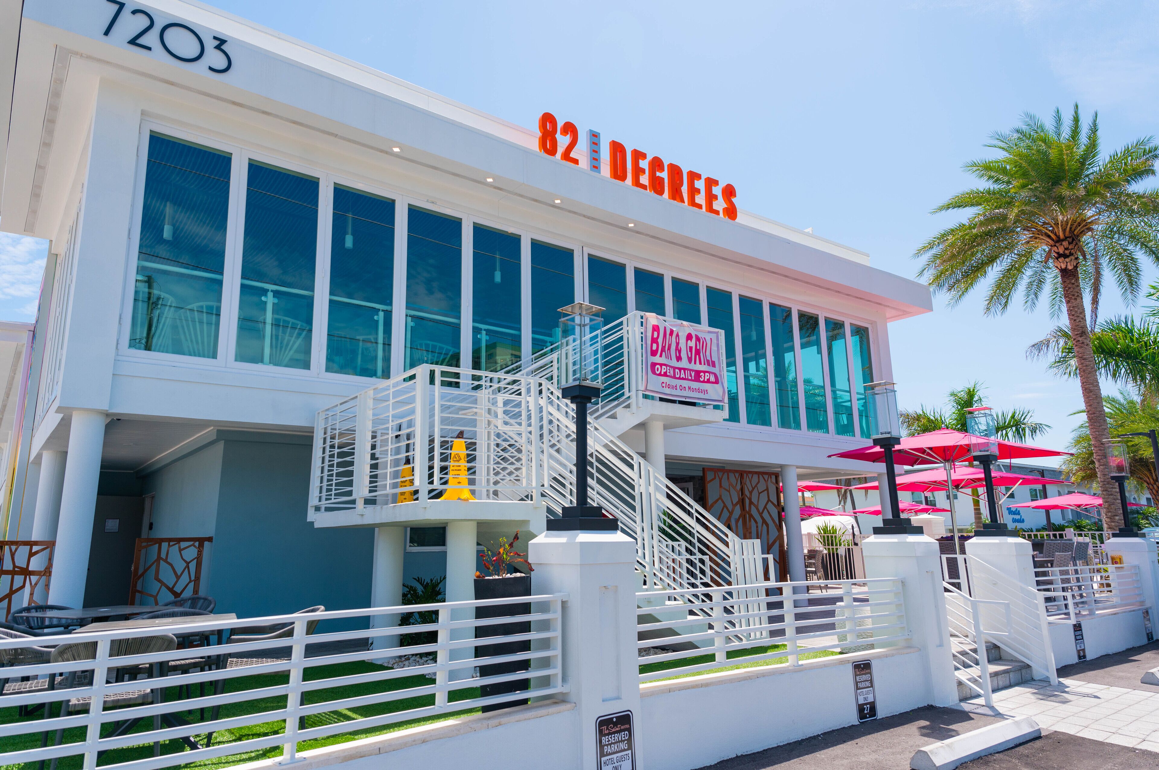 Un bâtiment moderne avec une enseigne indiquant « 82 DEGREES » et « B&B & GRILL OUVERT TOUS LES JOURS À PARTIR DE 15H ».