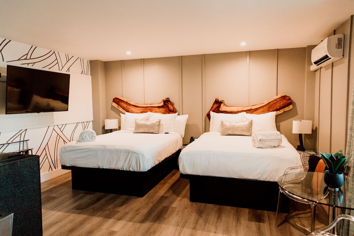 Ein Hotelzimmer mit zwei Betten, einem Fernseher, einem Schreibtisch und einem Sessel.