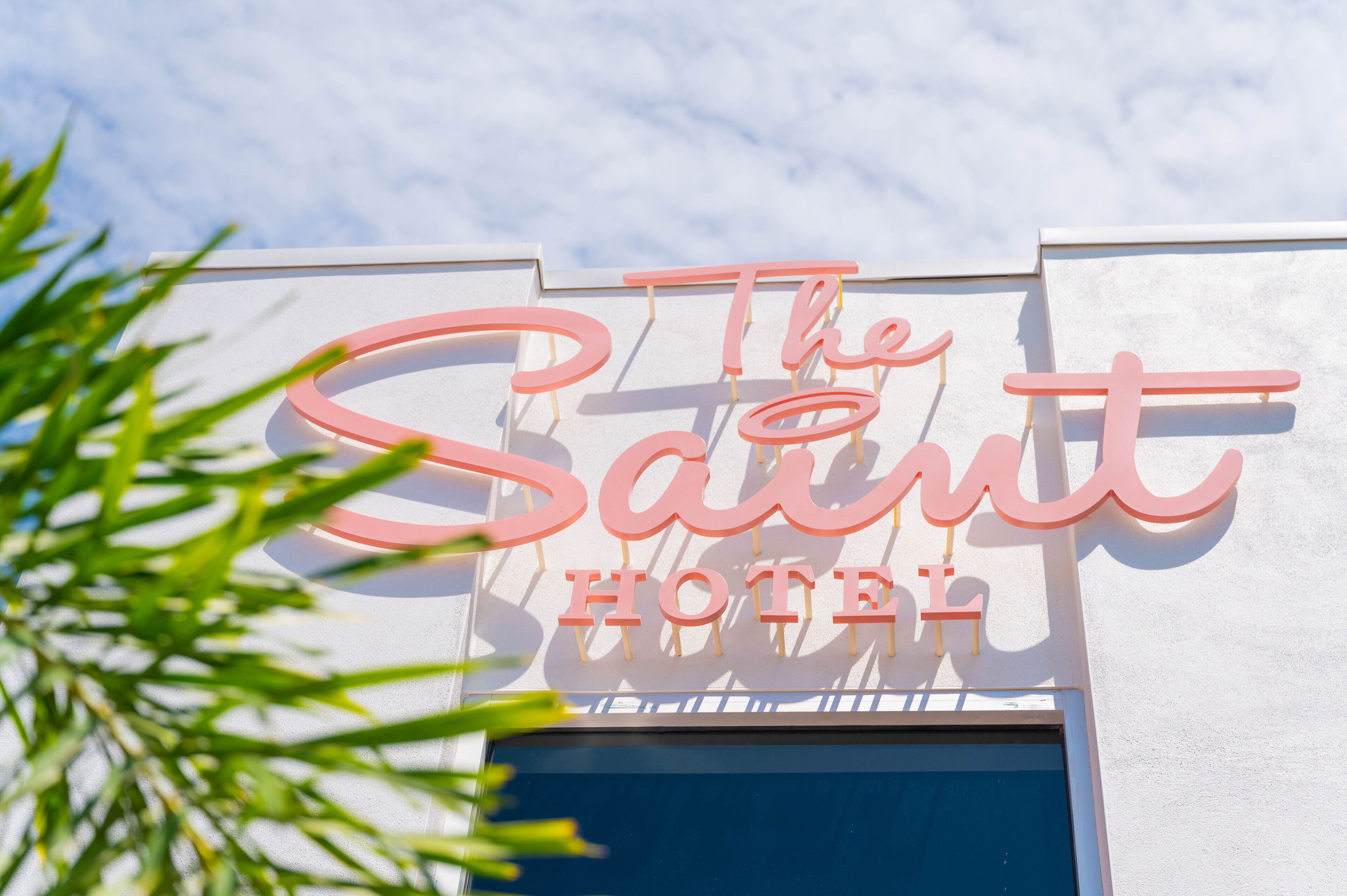 Une enseigne d’hôtel avec le nom « The Saint Hotel » écrit en grandes lettres roses.