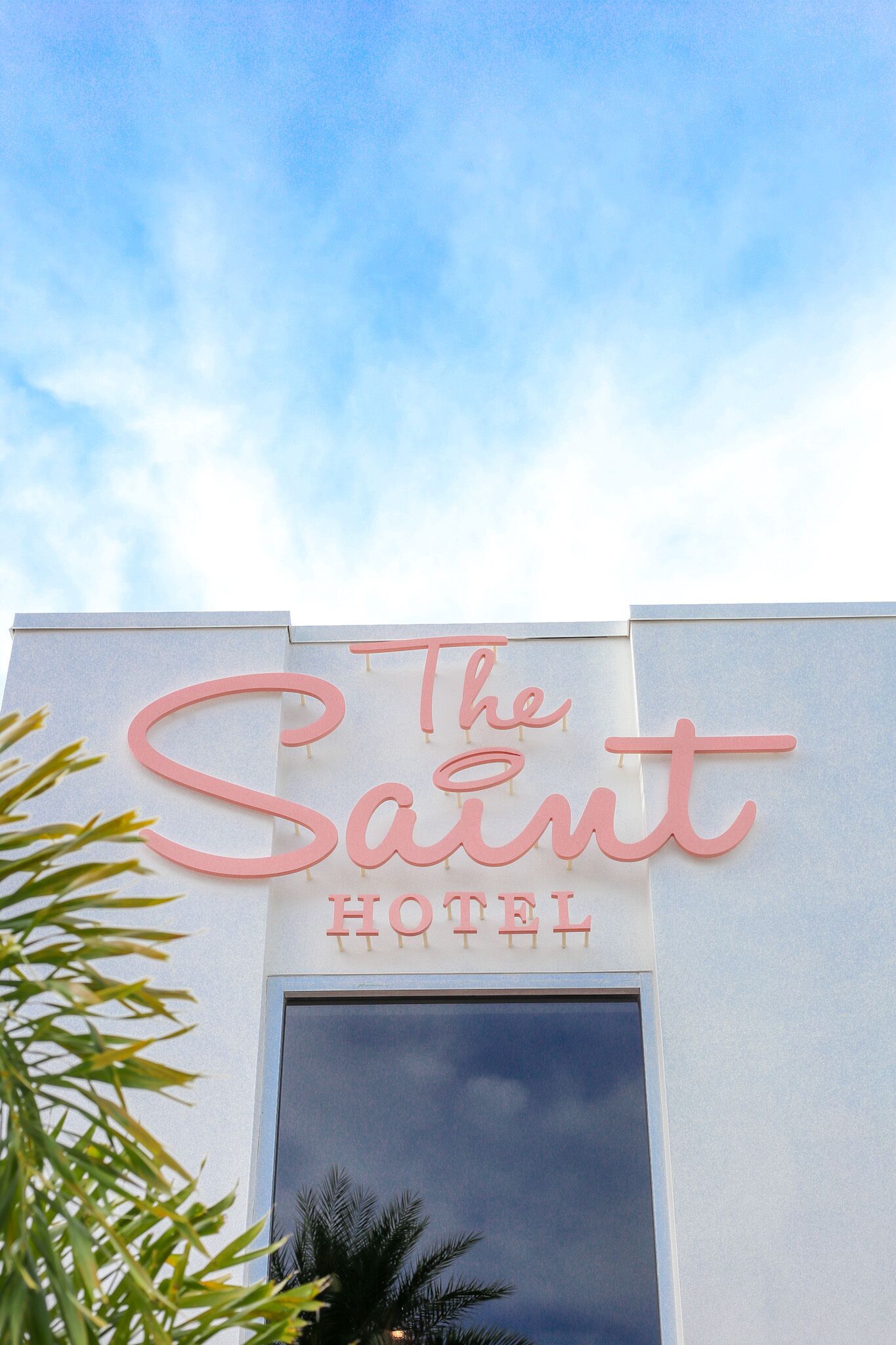 A hotel sign with the name "The Saint Hotel" in large pink letters.