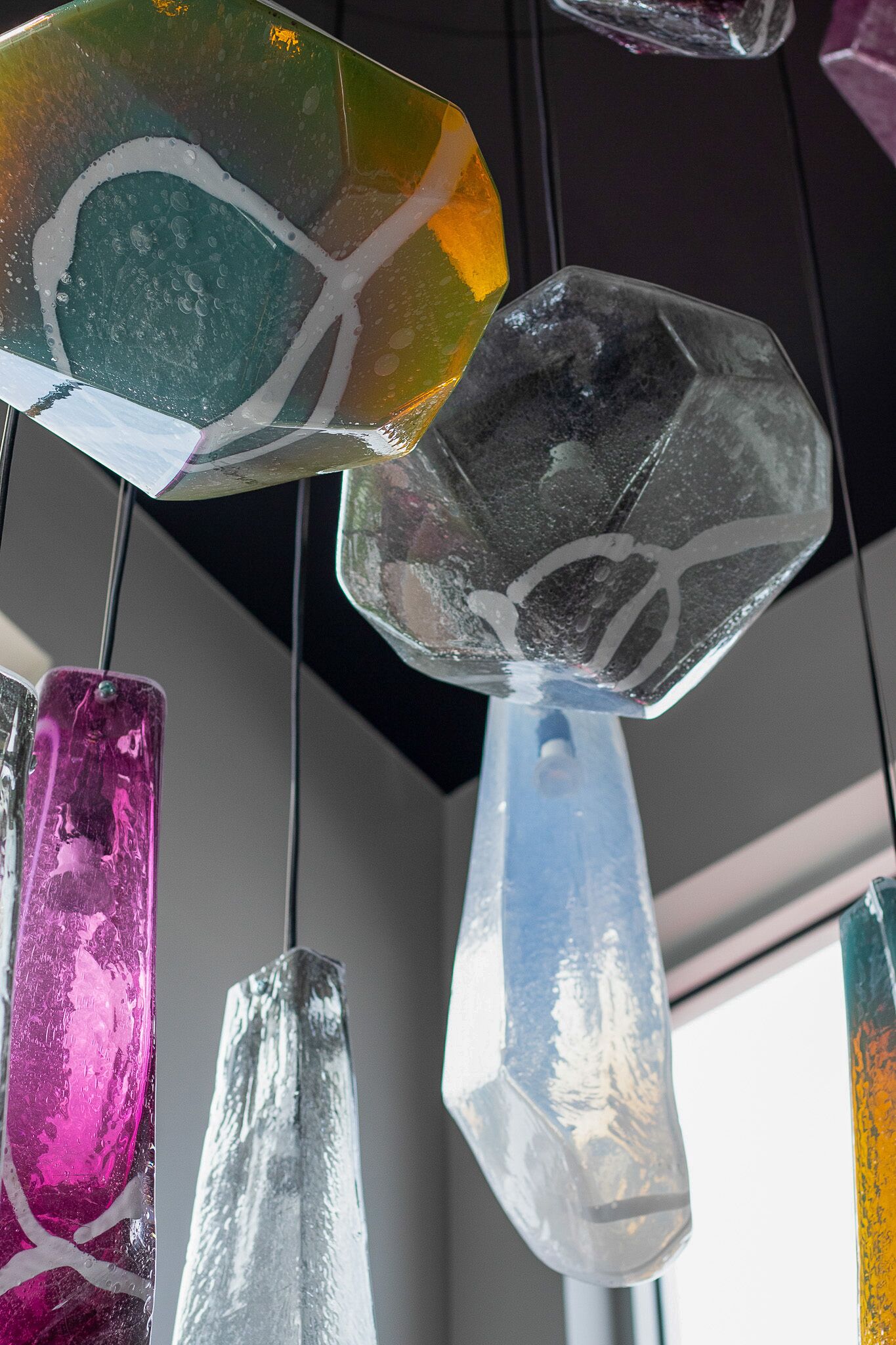Primer plano de varias piezas de arte en vidrio, con formas geométricas y diseños abstractos.