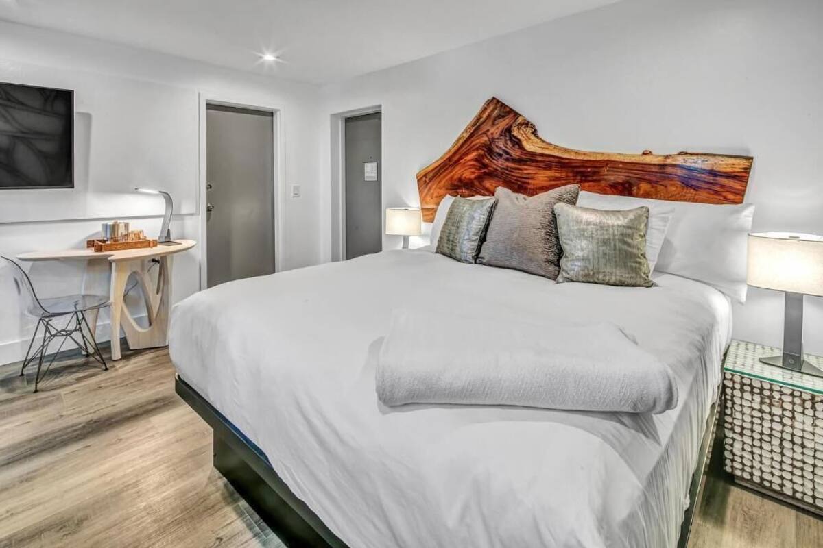 Ein modernes Hotelzimmer mit einem großen Bett, einem Schreibtisch und einem an der Wand hängenden Kunstwerk.