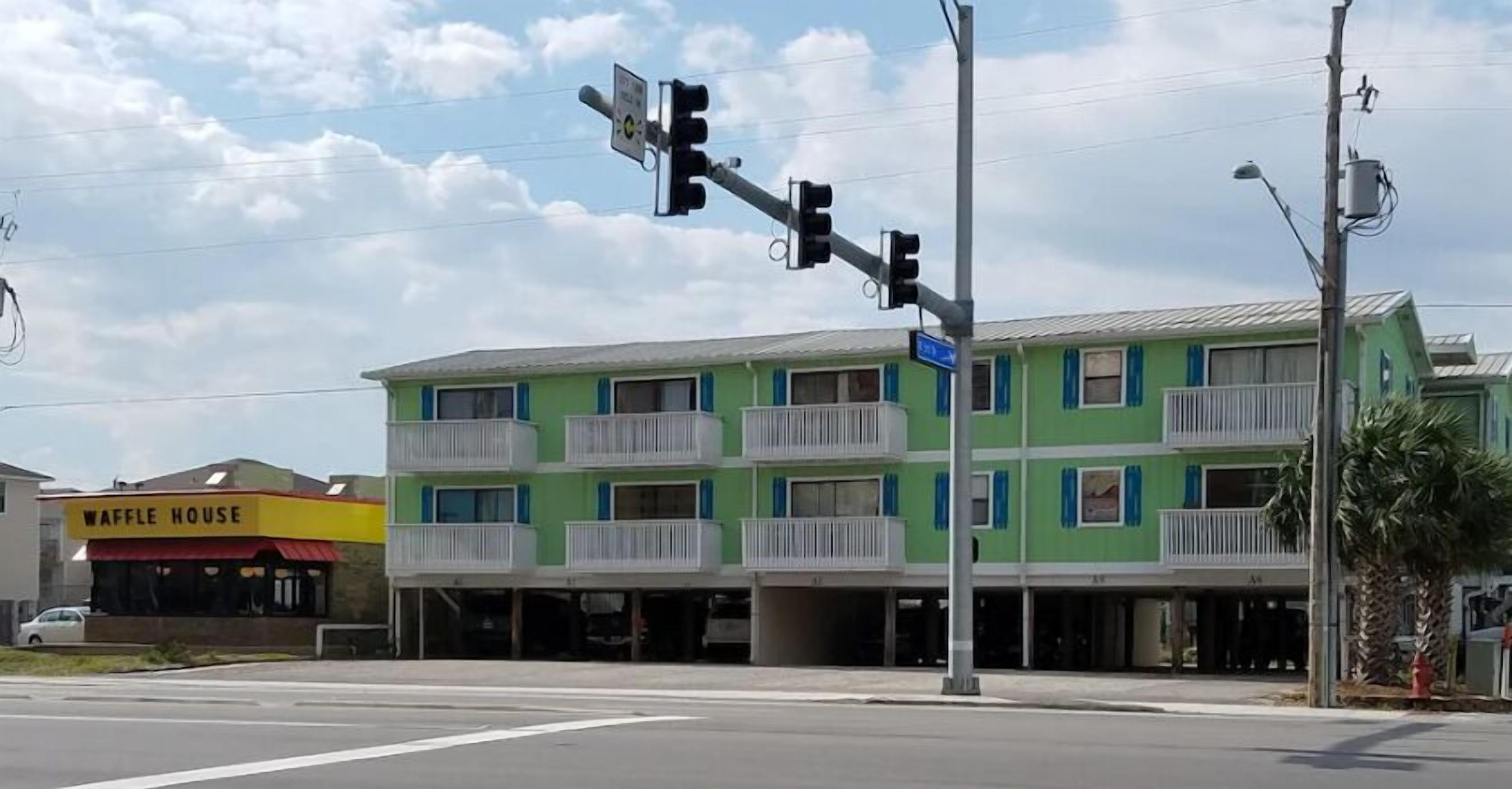 A multi-story building with balconies, a waffle house restaurant, and a traffic light.