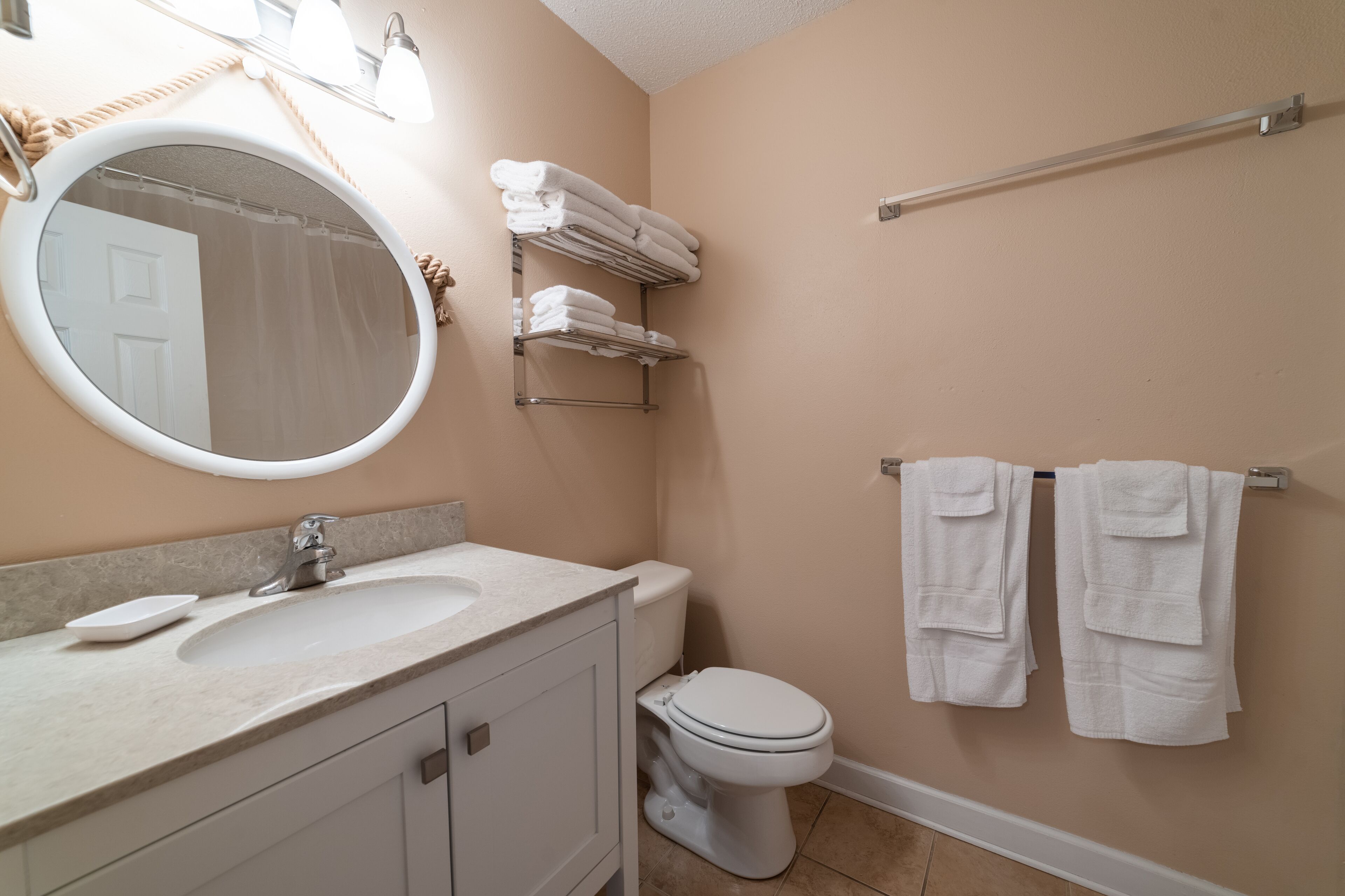 A bathroom with a sink, mirror, towel rack, and toilet.