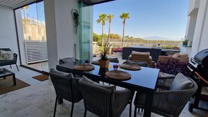 A modern outdoor patio with a dining table, chairs, and a grill.