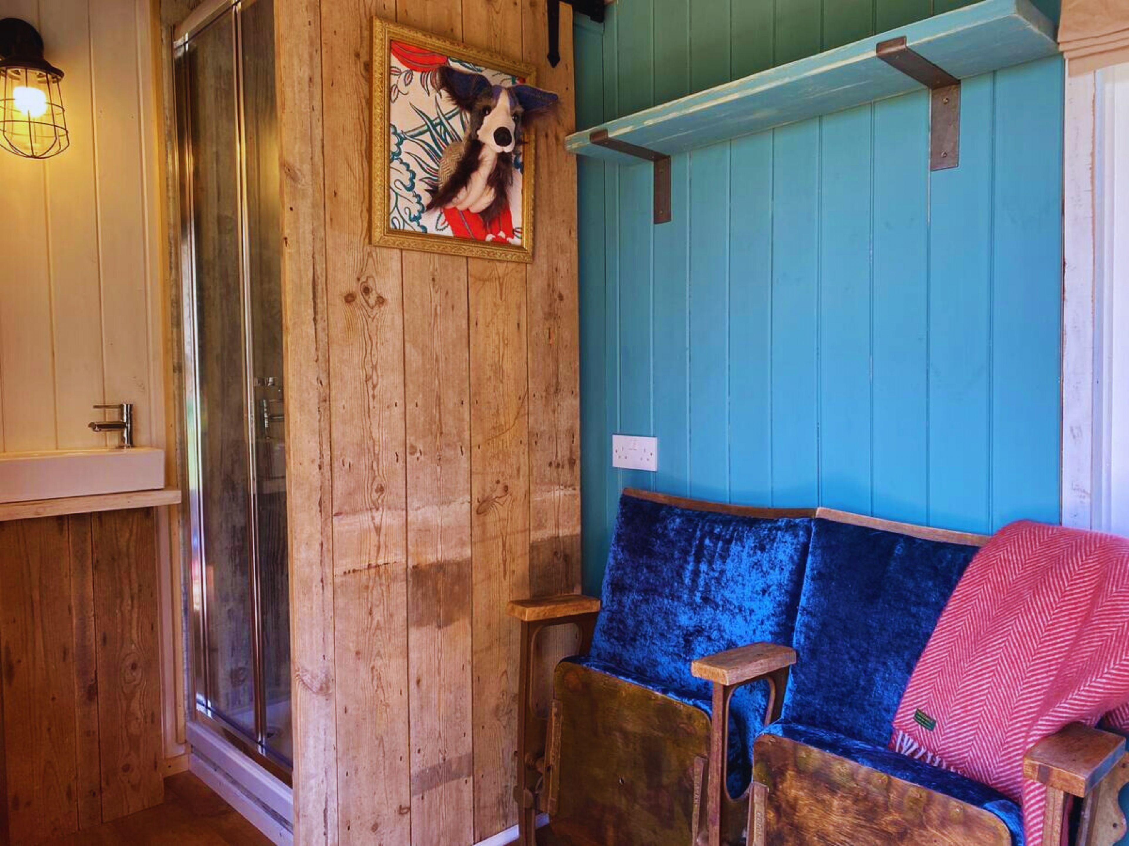 Un interno in legno con una parete blu, una panca di legno e un quadro con un cane.