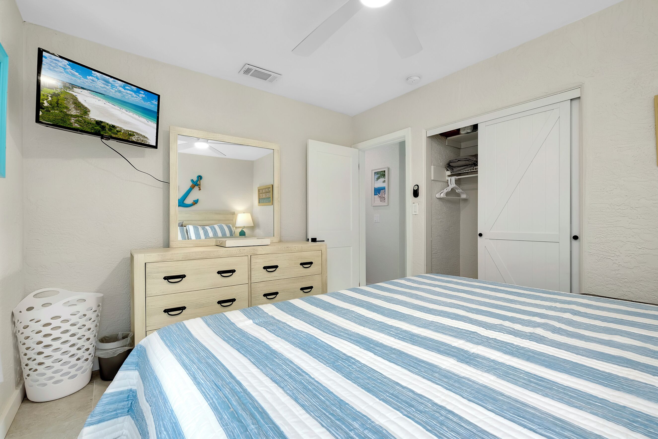 Une chambre à coucher comprenant un lit, une commode, un miroir, une télévision et un placard.