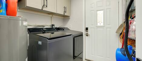 Cocina compacta con lavadora, secadora y una puerta con ventana.