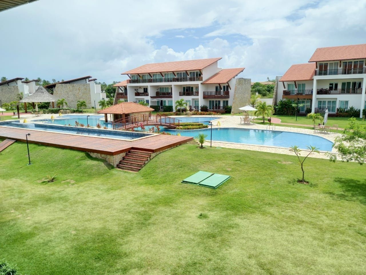 Ein Hotel mit mehreren Gebäuden, einem Schwimmbad und einem gepflegten Rasen.