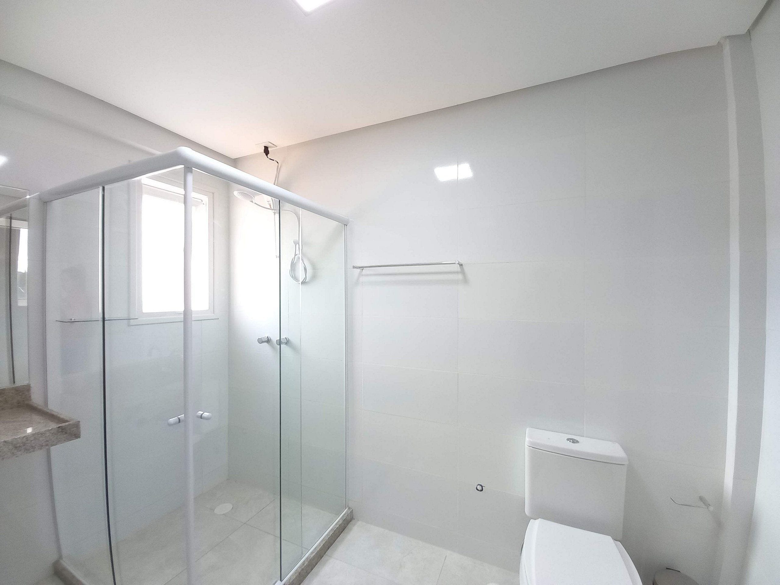 Un baño moderno con cabina de ducha de vidrio, inodoro y lavamanos.