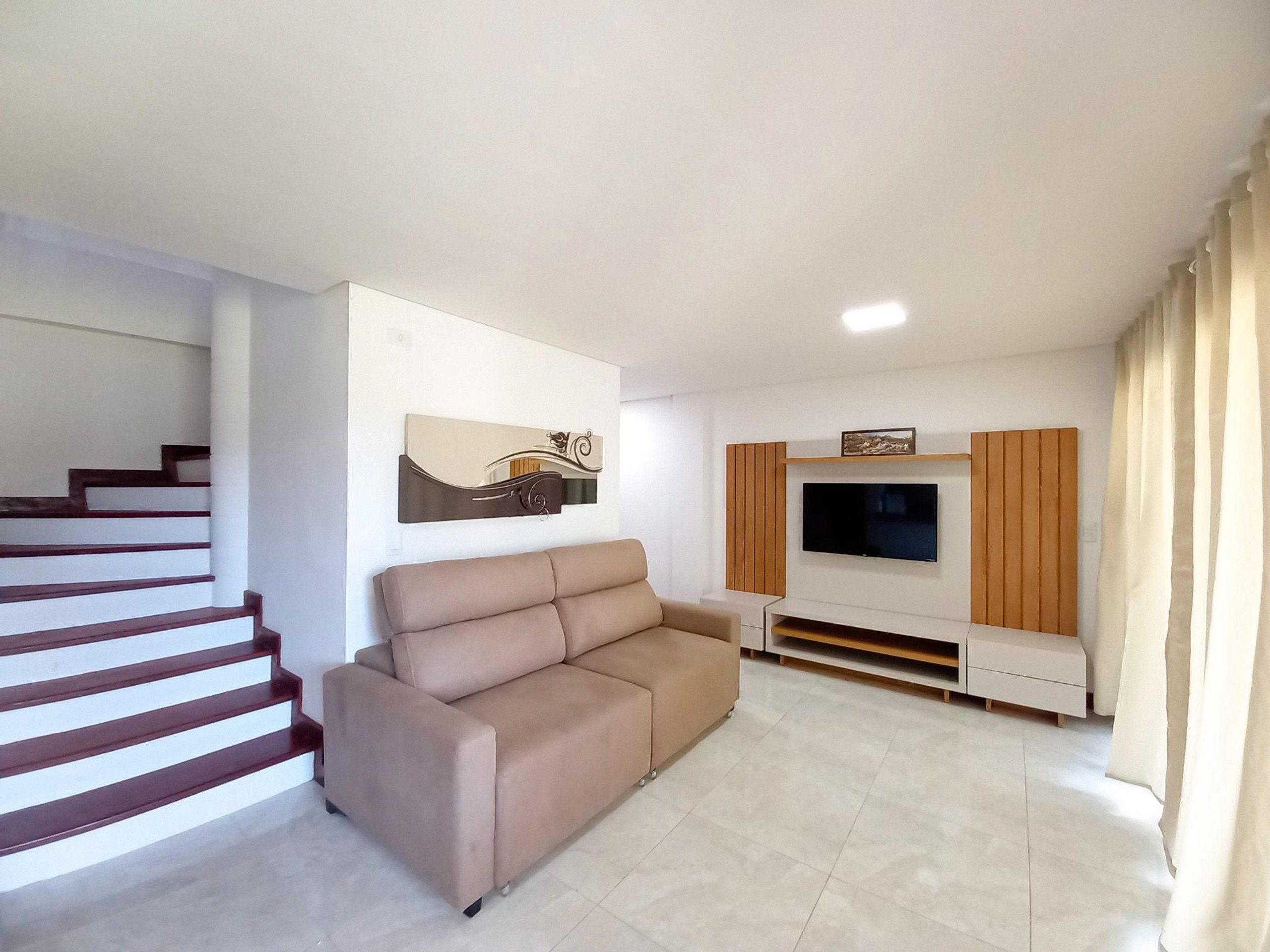 Een moderne woonkamer met een bank, een flatscreen-televisie en een trap.