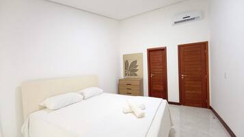 Een slaapkamer met een bed, een dressoir, twee deuren en een airconditioning.