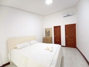 Une chambre à coucher comprenant un lit, une commode, deux portes et un appareil de climatisation.