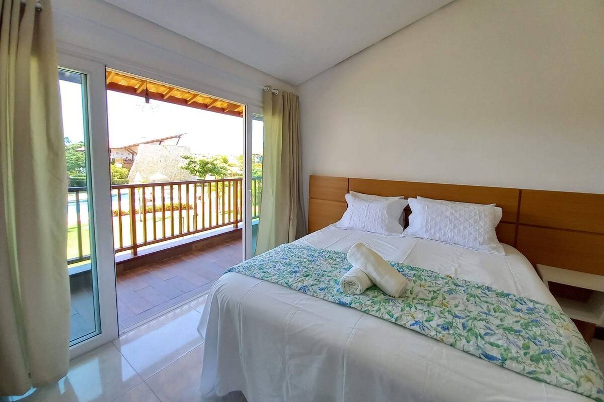 A hotel room with a bed, a balcony, and a view of the outside.