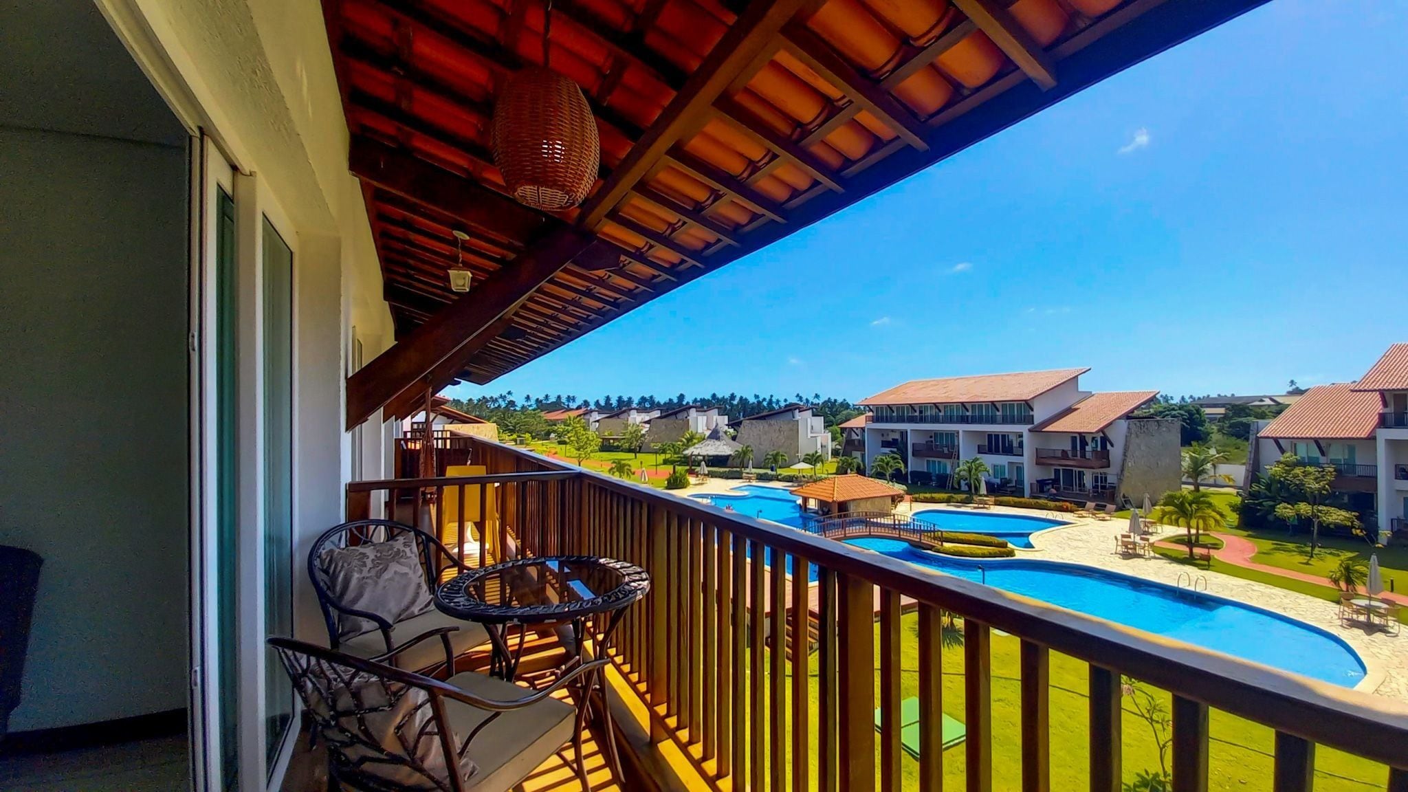 A balcony with a view of a swimming pool and resort buildings.