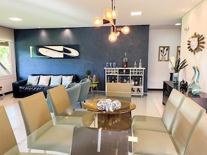 A modern living room with a glass coffee table, leather sofa, and a decorative wall piece.
