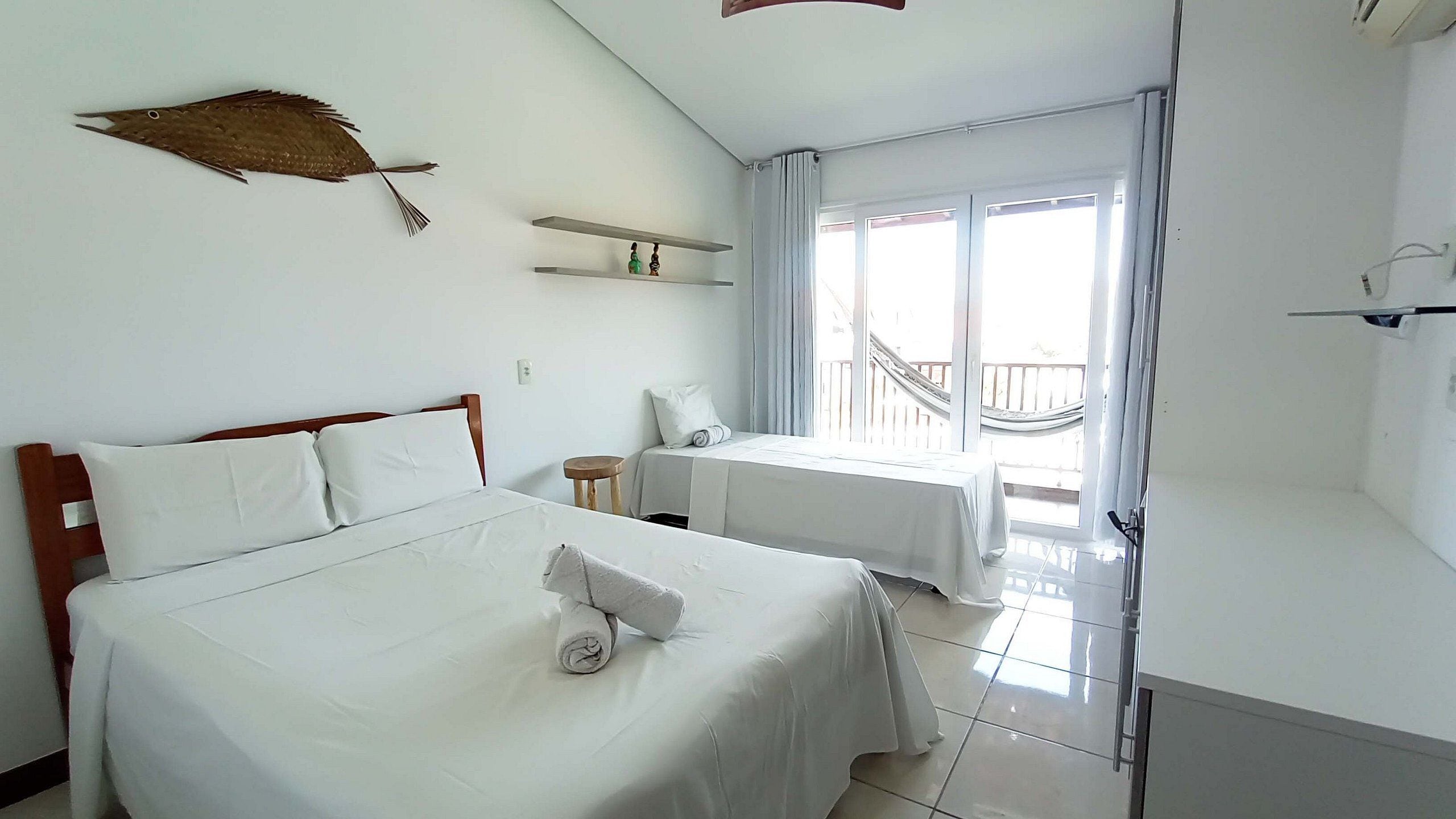 A hotel room with a bed, a small table, a window with a view, and a balcony.