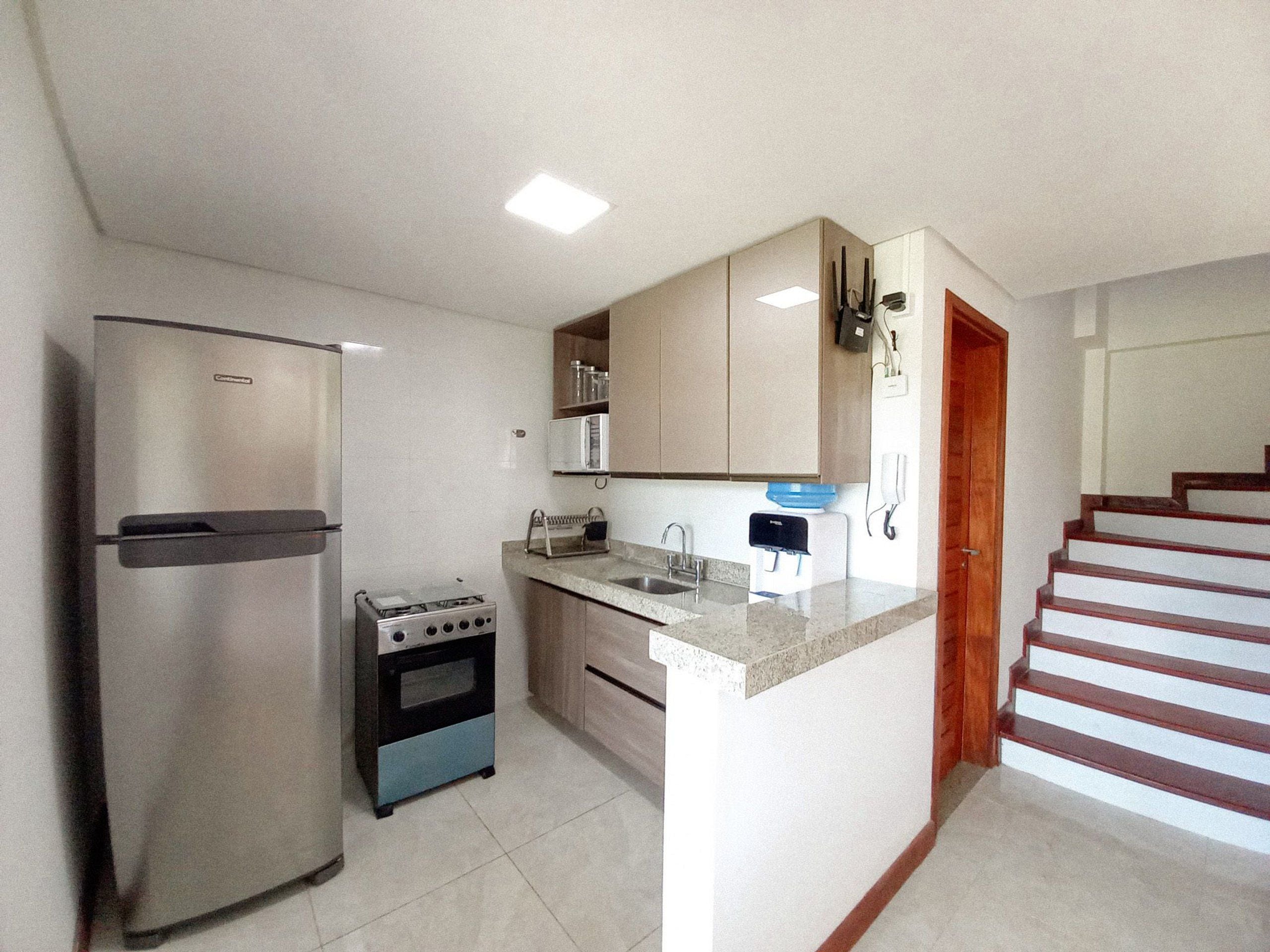 A compact kitchen with a refrigerator, stove, microwave, and sink.