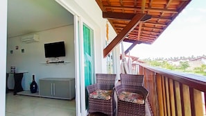 Un balcon avec des fauteuils en osier, un téléviseur à écran plat et un distributeur d’eau.