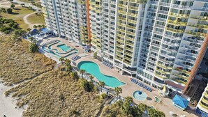 A high-rise hotel with multiple balconies, a swimming pool, and a beach area. - North Myrtle Beach Oceanfront Condo w Lazy River (North Myrtle Beach)