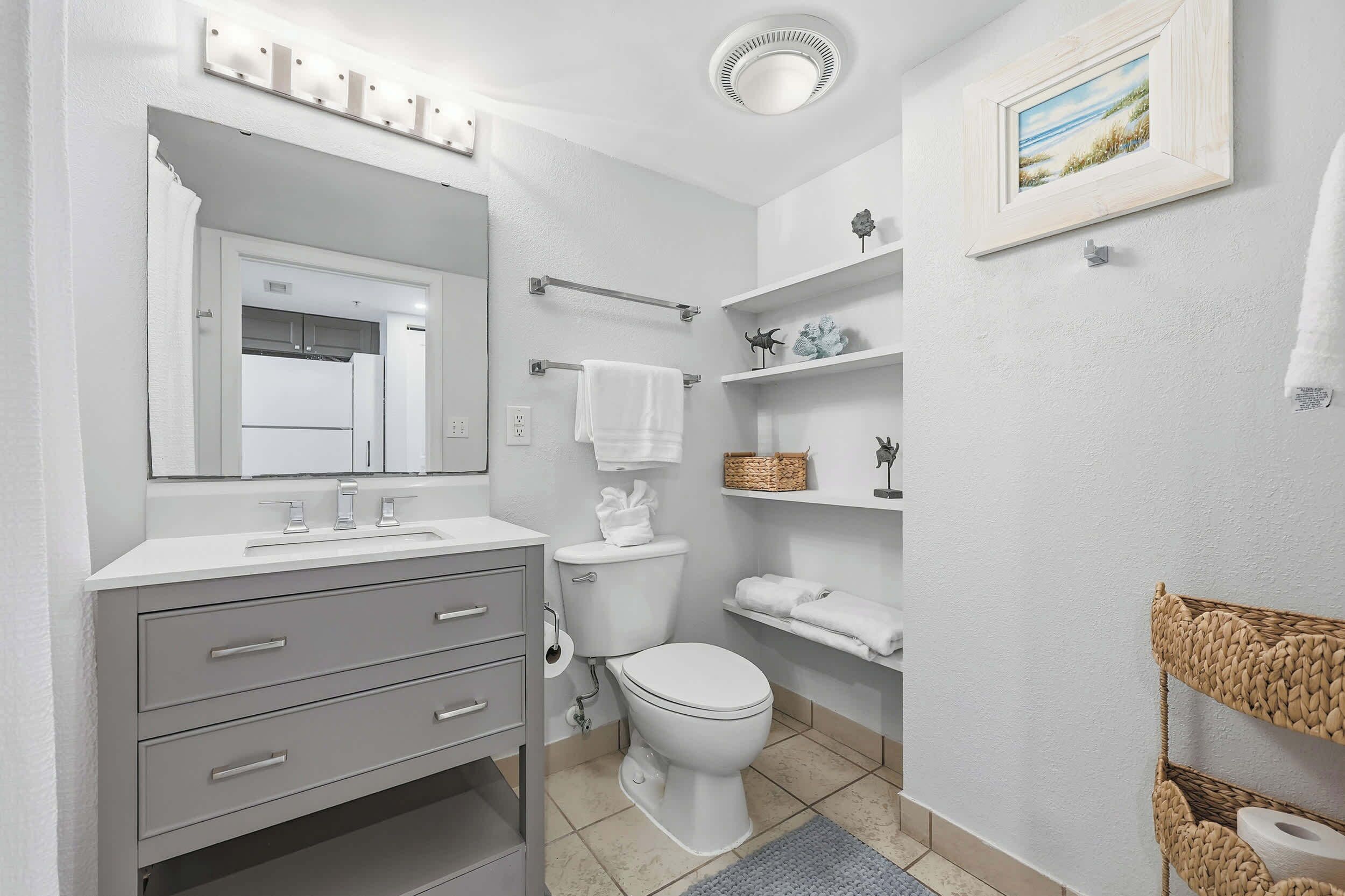 Een moderne badkamer met een wit wastafelmeubel, toilet en planken.