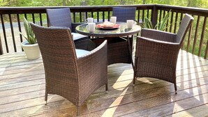Une terrasse extérieure avec des meubles en osier, une table en verre et une plante en pot.