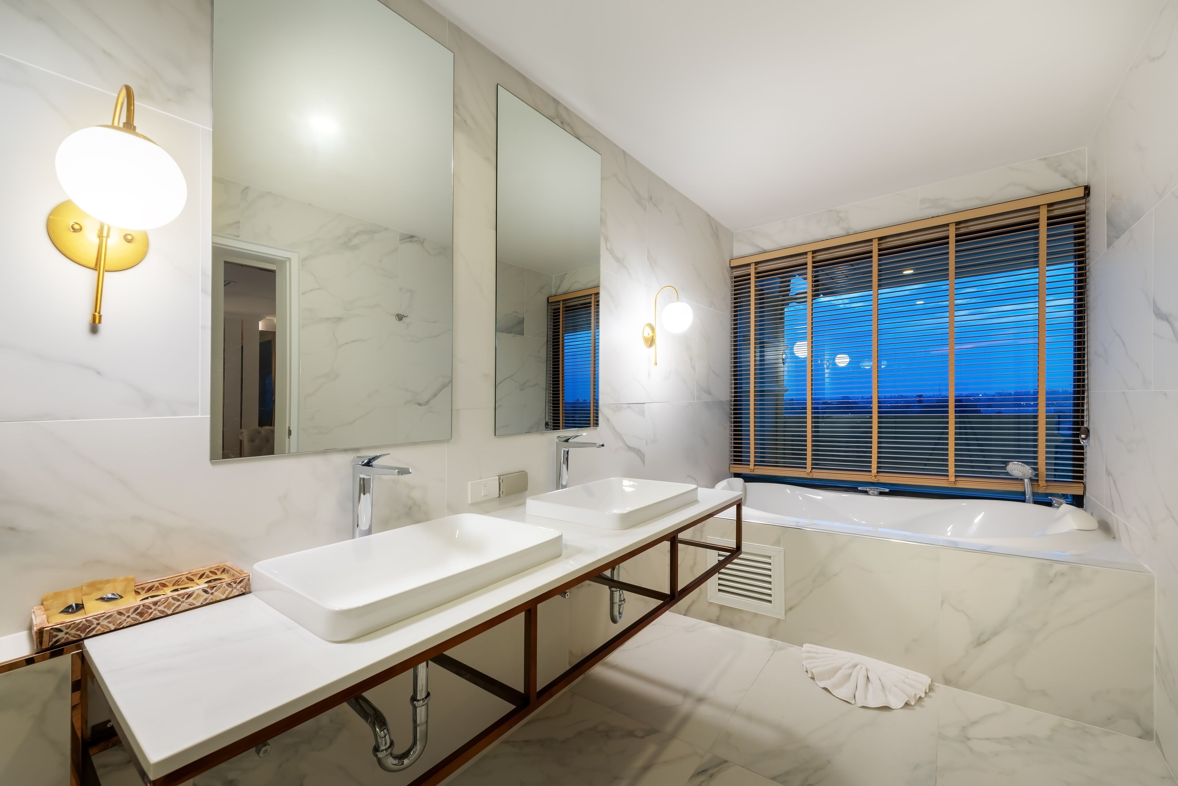 A modern bathroom with two sinks, a large mirror, and a bathtub.