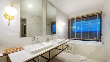 A modern bathroom with two sinks, a large mirror, and a bathtub.