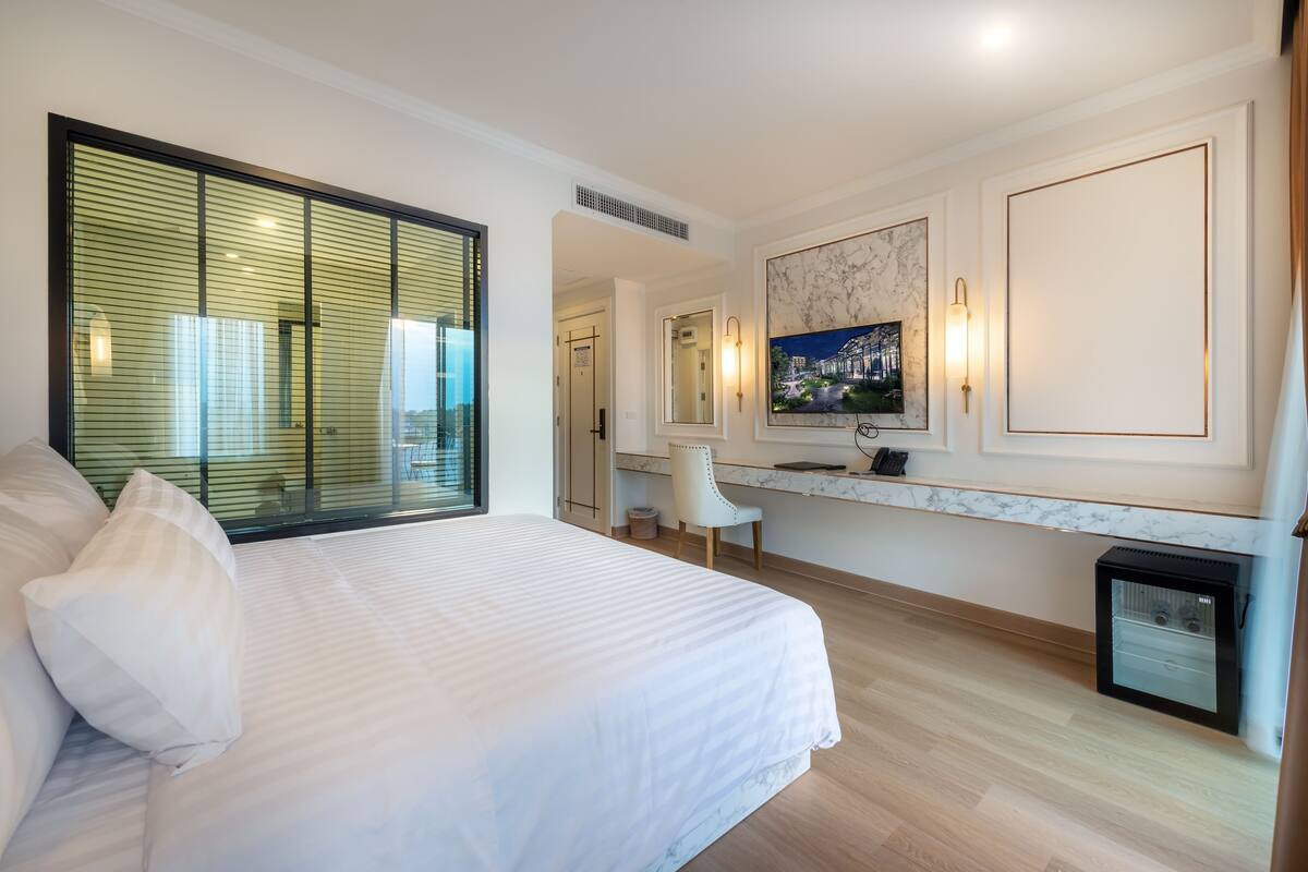 Una habitación de hotel moderna con una cama grande, un escritorio, una silla y un pequeño cubo de basura.