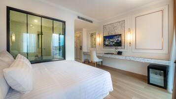 A modern hotel room with a large bed, a desk, a chair, and a small trash bin.