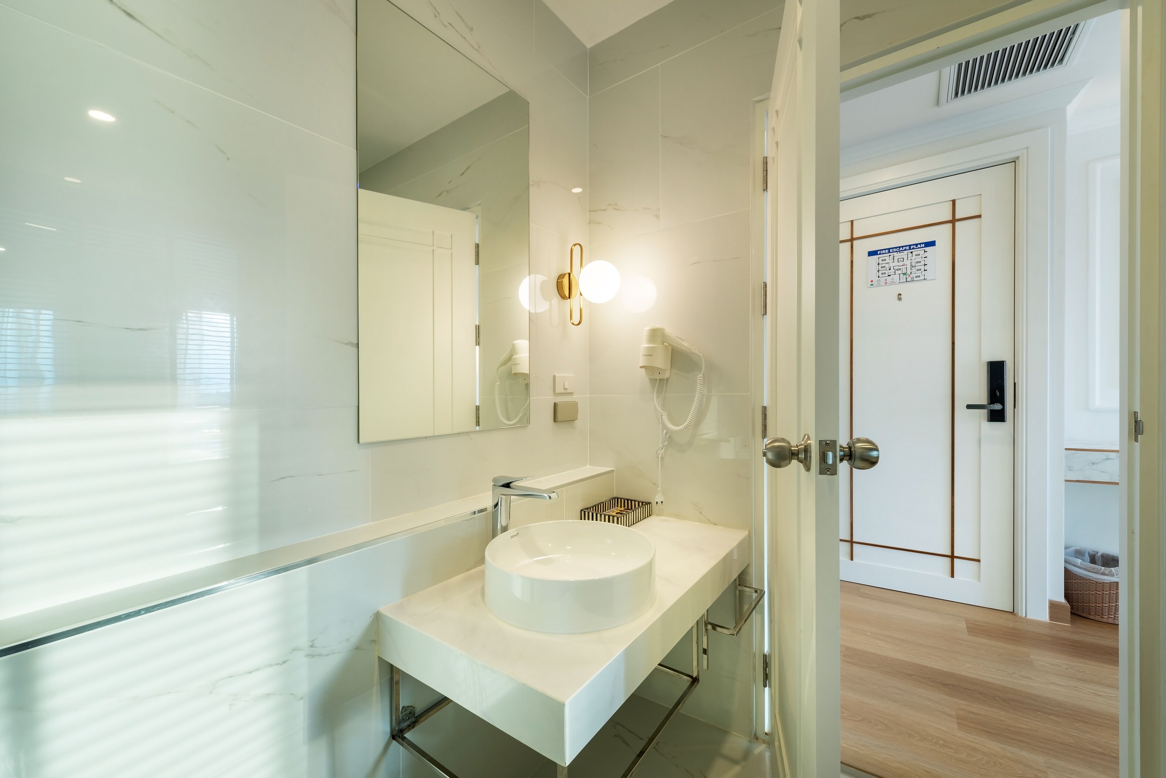 A modern bathroom with a white sink, a large mirror, and a light fixture above it.