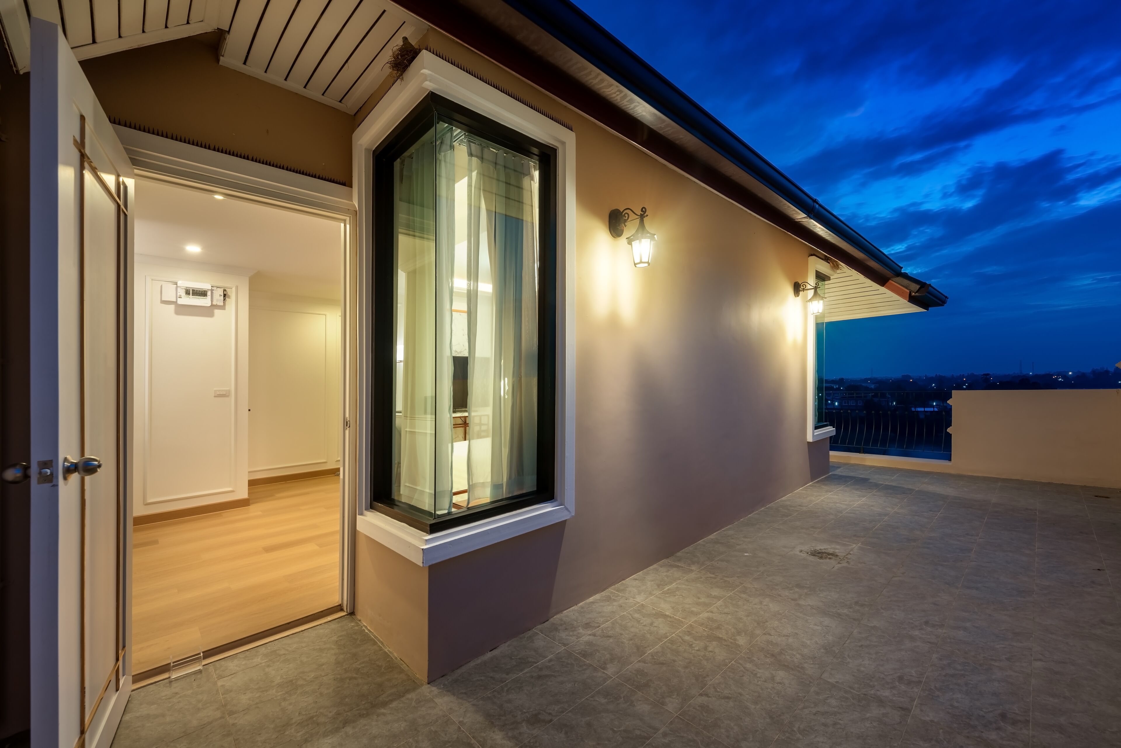 A modern building exterior with a large window, a door, and a light fixture.