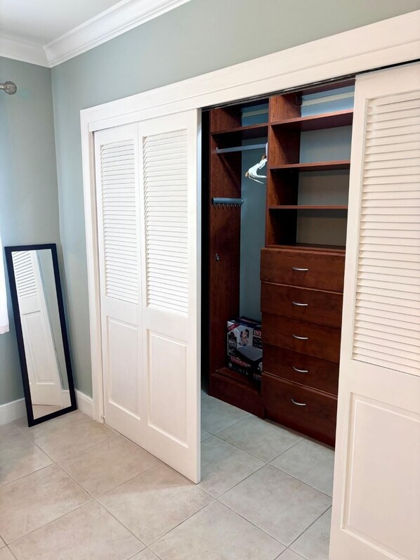 Un vestidor con puertas blancas, estanterías de madera y un espejo.