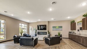 Un salón moderno con chimenea, asientos cómodos y una cocina con armarios oscuros y encimera.
