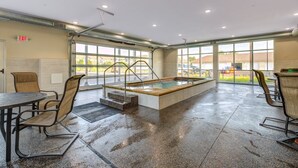 Un área de piscina húmeda con jacuzzi, sillas y una mesa.