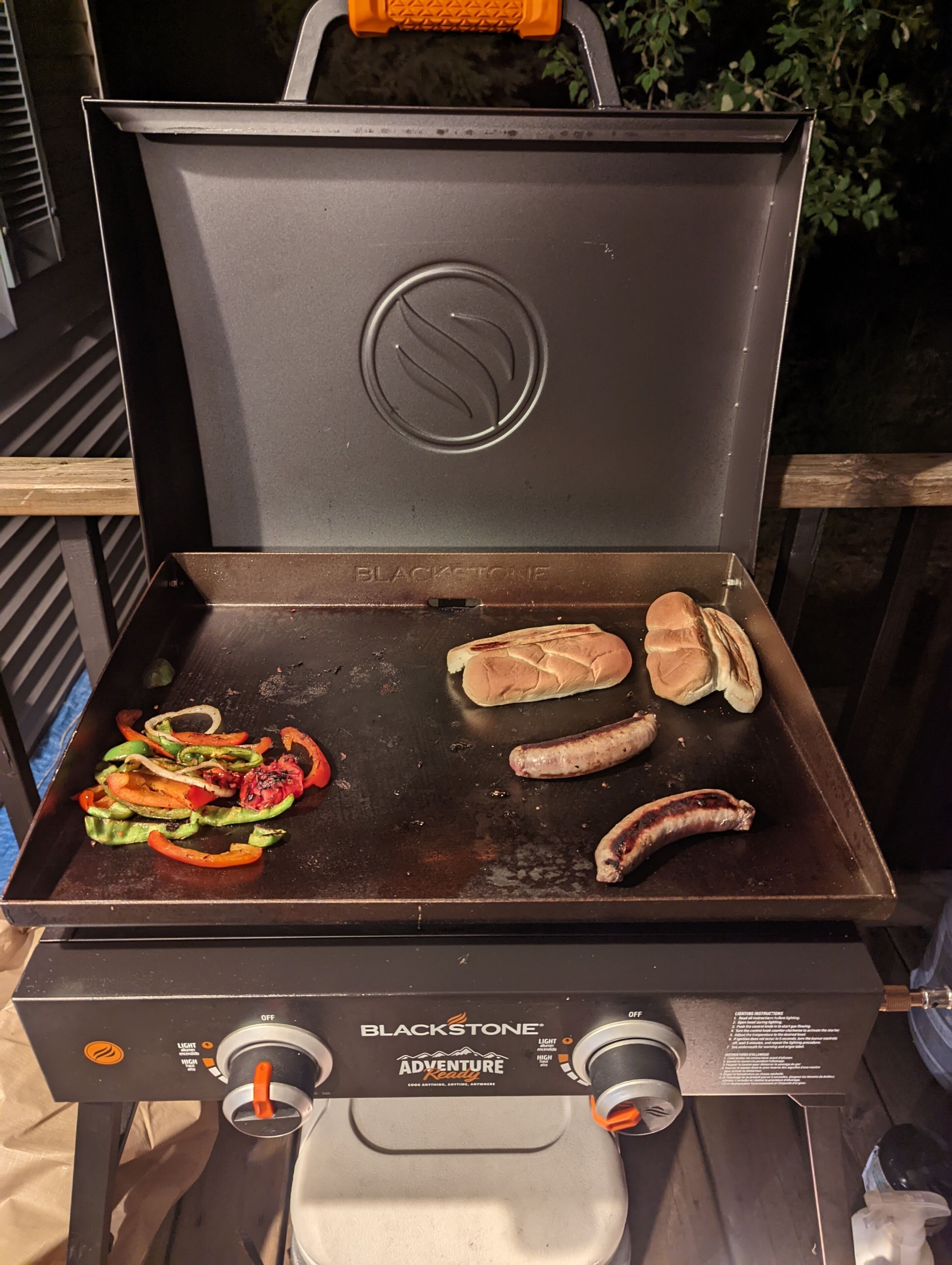 Ein Blackstone Adventure Kelly Grill mit Bratgemüse und Würstchen.