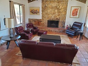 A living room with a stone fireplace, leather sofas, a coffee table, and a lamp.