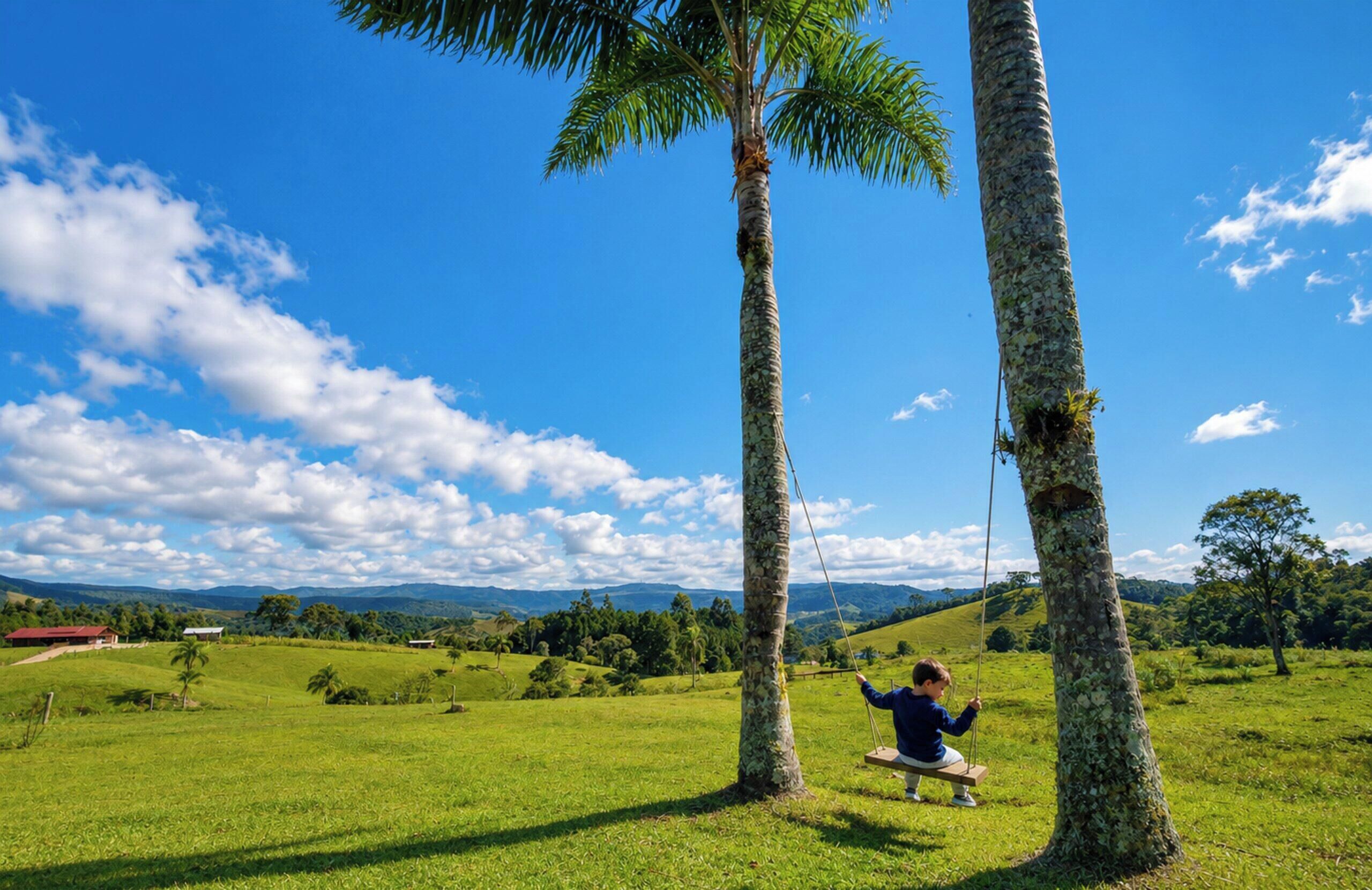 A child on a swing between two palm trees in a grassy field with a clear sky.