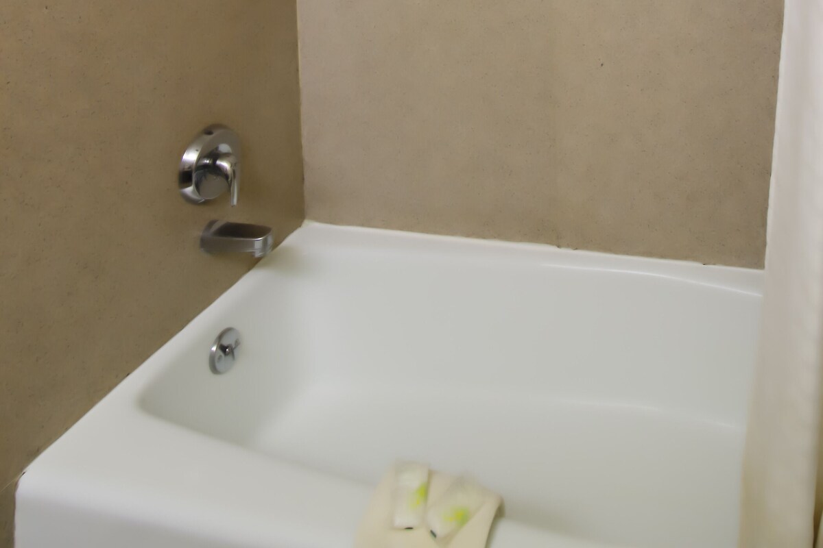 A bathroom with a white bathtub, a showerhead, and a towel rack.