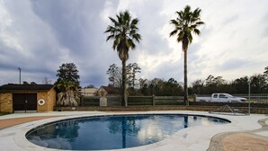 Une piscine à bord incurvé, entourée d’une terrasse dallée.