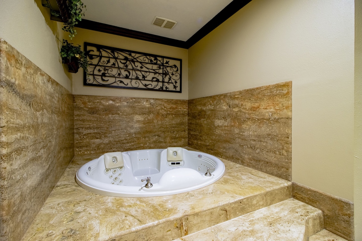 A bathroom with a freestanding bathtub, stone walls, and a decorative wall piece.