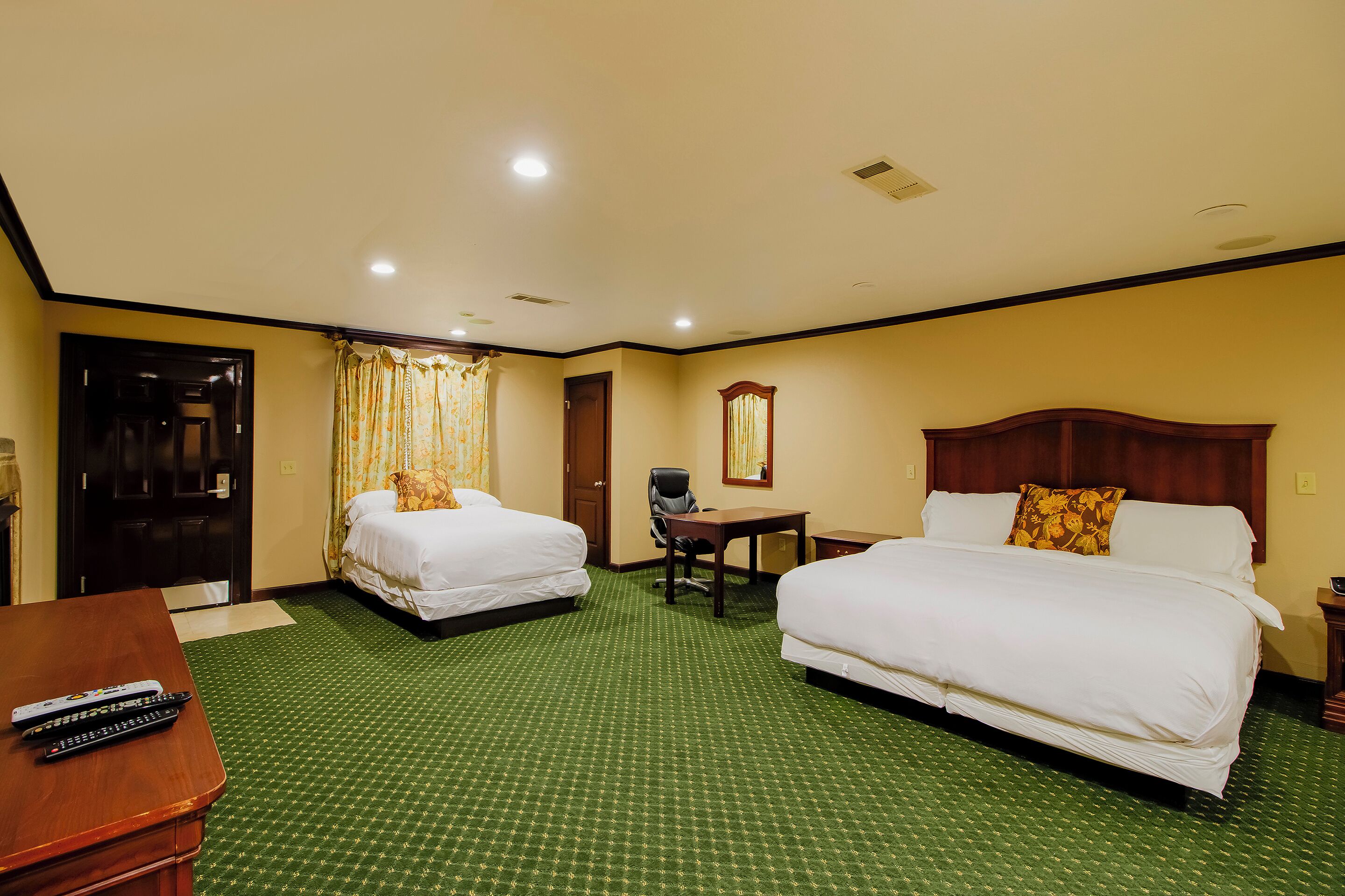 A hotel room with two beds, a desk, a chair, and a TV.