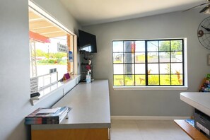 A reception area with a counter, a mounted television, a window with a view of the outside, and a clock on the wall. - OYO Pinewood Inn & Suites Silsbee (Silsbee)