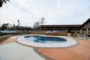 Piscina com design curvo, rodeada por um espaço pavimentado com uma mistura de azulejos claros e escuros.