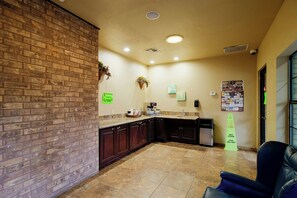 A lobby with a brick wall, a wet floor sign, a reception desk, and a seating area. - OYO Pinewood Inn & Suites Silsbee GA (Silsbee)