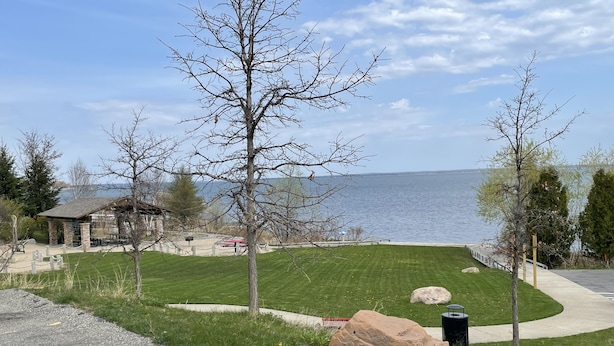 Un parc au bord du lac, équipé de tables de pique-nique, d’un kiosque et d’un grand rocher décoratif.