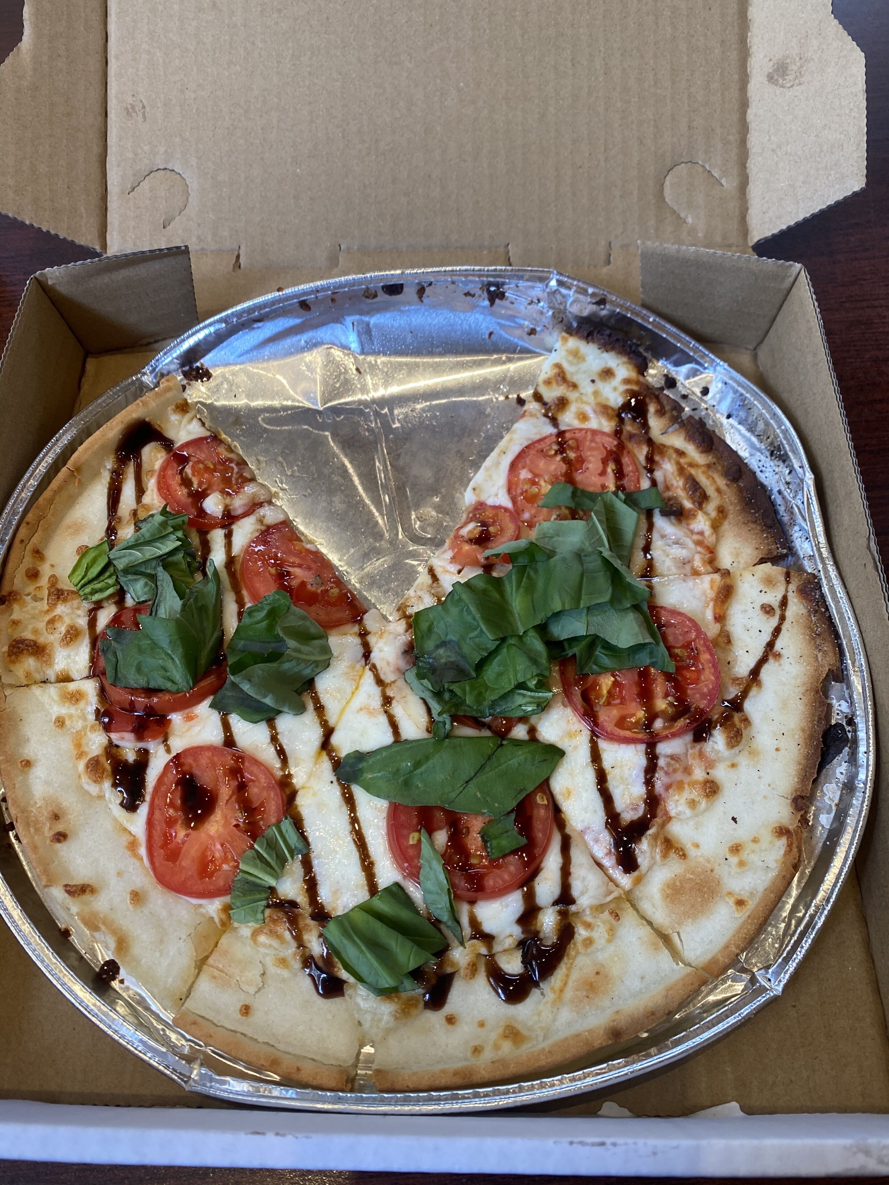 Pizza numa caixa de cartão com revestimento de papel alumínio.