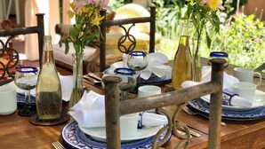 Ein Holztisch, gedeckt mit blau-weißen Tellern, verschiedenen Gläsern und floralen Tischdekorationen.