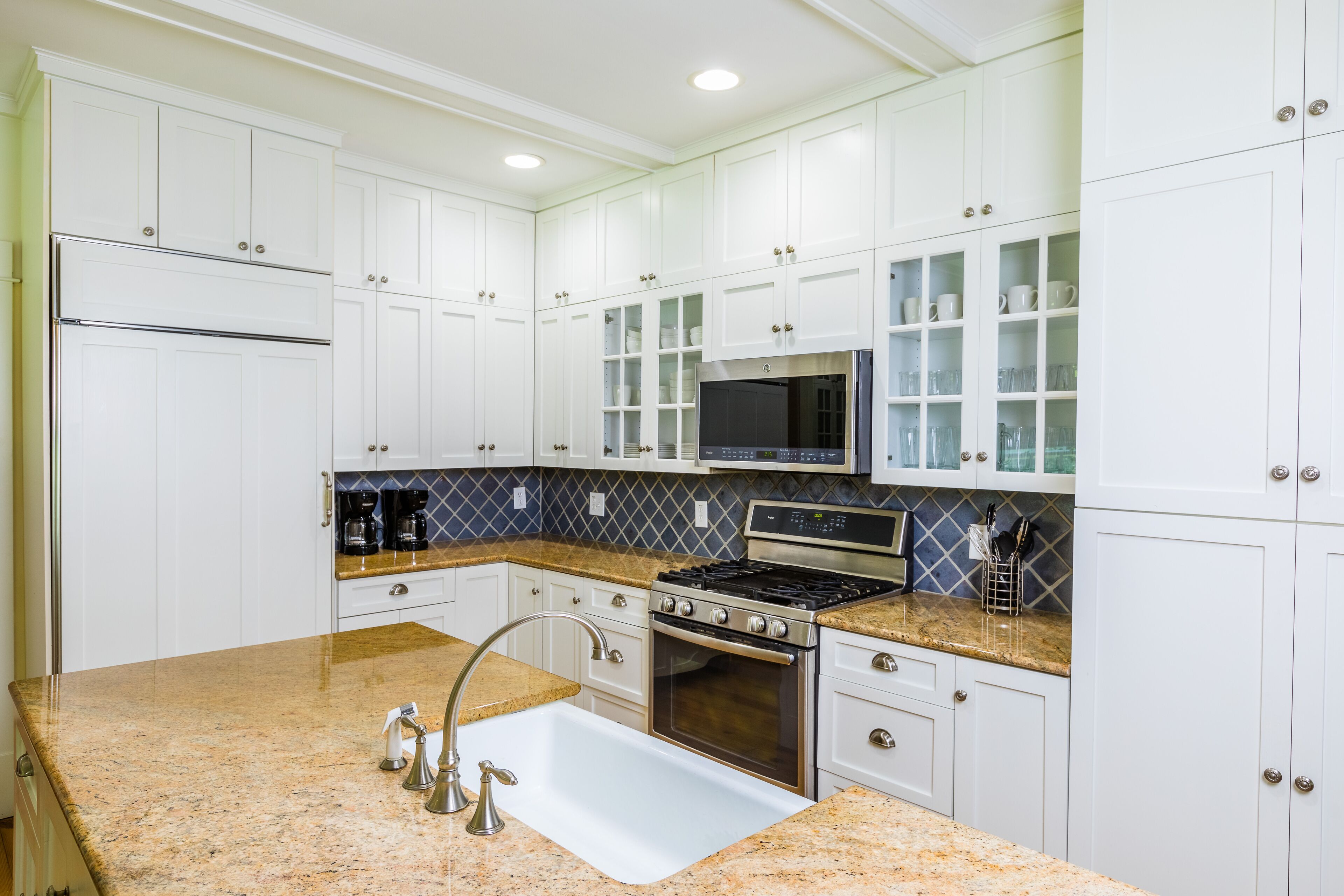 A kitchen with white cabinets, a granite countertop, stainless steel appliances, and a microwave.