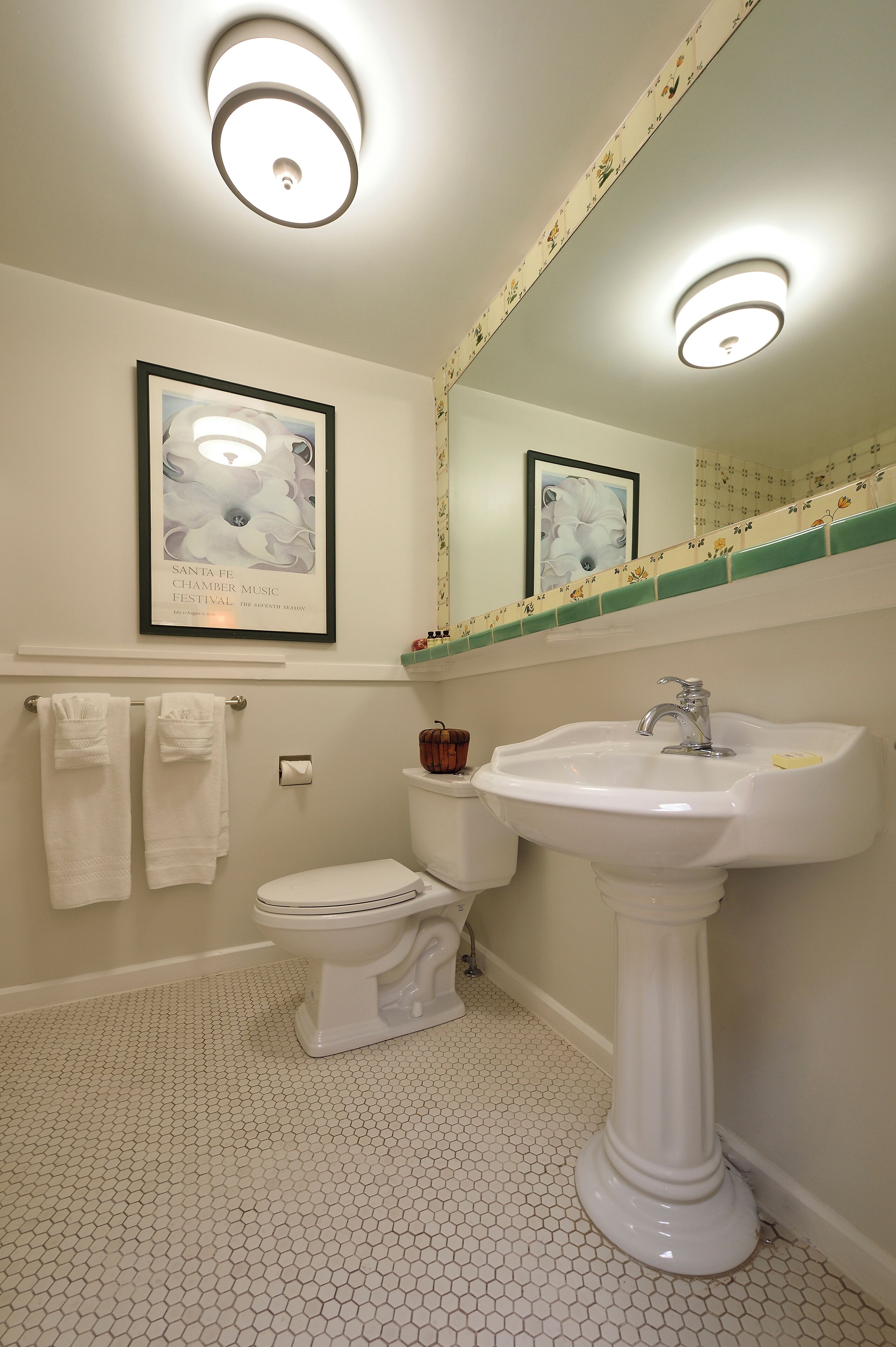 A bathroom with a toilet, sink, and framed artwork on the wall.
